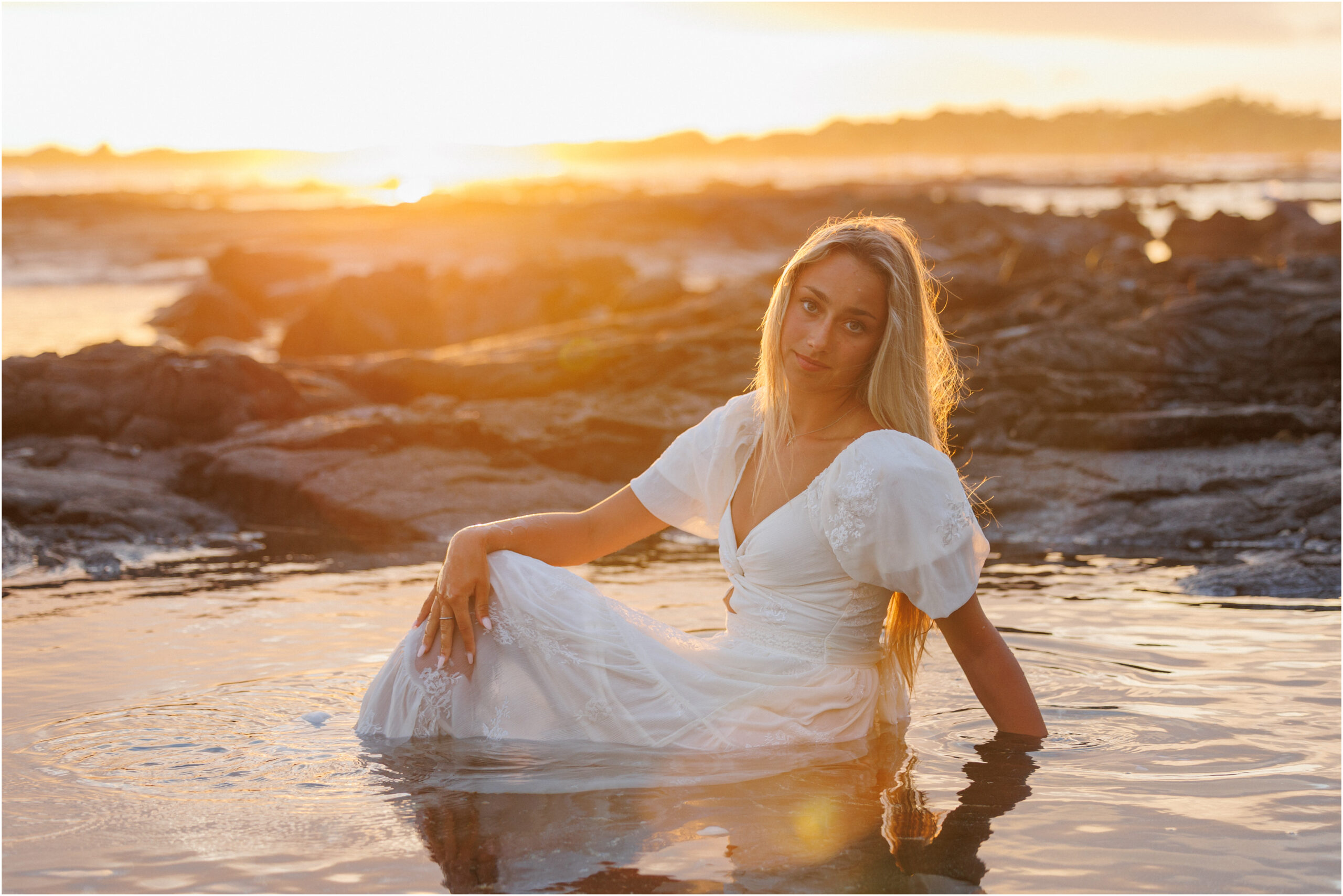 Beach portrait at sunset, in the water in a white dress